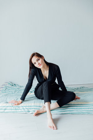 Slim fashion woman in black clothes sitting on the floorの写真素材