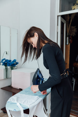Woman housewife ironing washed clothes with iron on boardの写真素材
