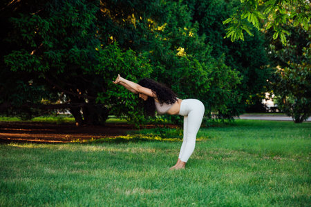 Athletic brunette woman doing gymnastics yoga asana on the grass in the parkの写真素材