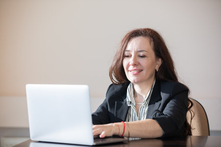 woman working on laptop online and smiling in officeの写真素材