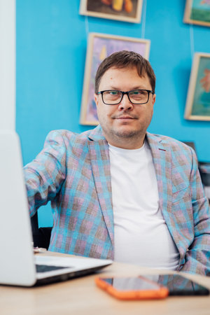 Business man with glasses at desk with laptop in office online