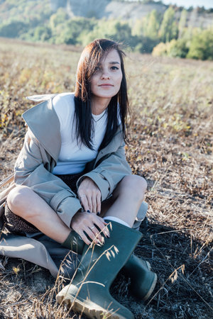 Beautiful fashionable brunette woman in sitting on an autumn field