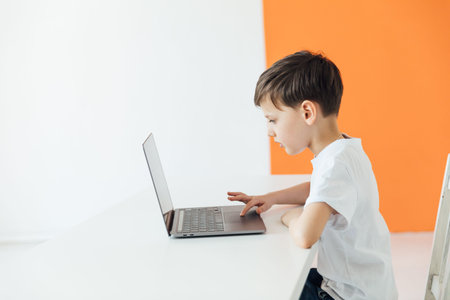 Boy working online at desk with study laptop at school