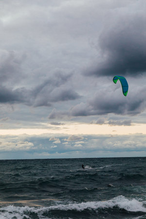 Kite surfing athlete riding waves in storm and wind