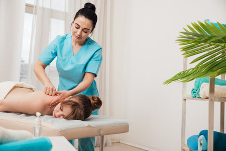 Massage therapist doing medical spa back and body massage to womanの写真素材