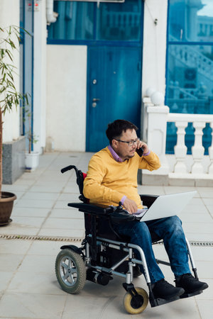 disabled businessman on a wheelchair at a window uses smartphone