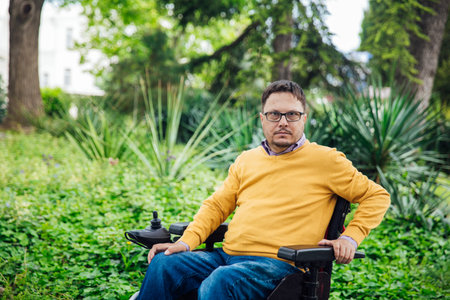 man sitting on a wheelchair look at playground in park feel sad. Paralyzed disease health care...