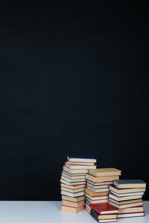 Stacks of old educational books for learning on a black backgroundの写真素材