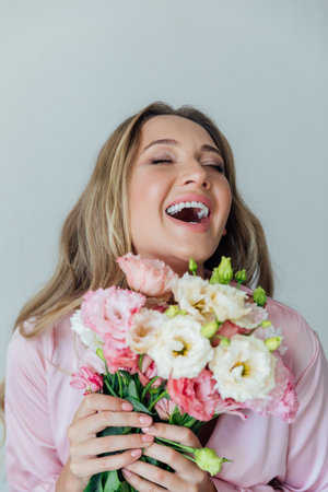 Blonde smiling in summer pink dress with bouquet of spring flowersの写真素材