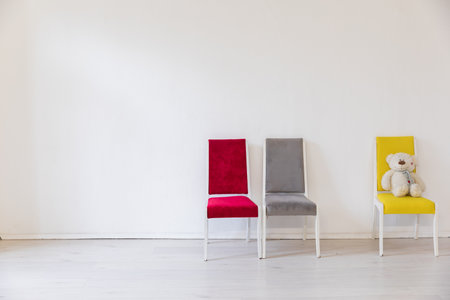 Three chairs of different colors in the interior of an empty white roomの写真素材