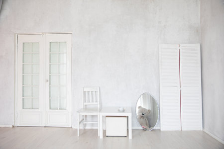 Chair, table and mirror in the interior of an empty white room with a doorの写真素材