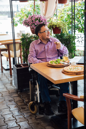 Man in wheelchair dining in restaurantの写真素材