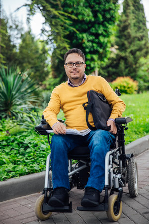 Shot back depressed man sitting on a wheelchair look at playground in park feel sad. Paralyzed disease health care desperation impairment. Slow motionの写真素材