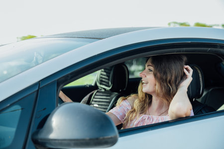 Excited young woman driving vehicle confidently, view from inside car interior at sunny day