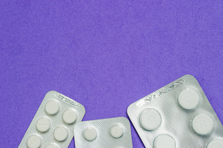 Three shiny packets of white pills on a blue background. Diseases, pharmaceuticals.