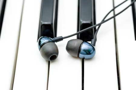 Stylish black headphones lie on the keys of the synthesizer.