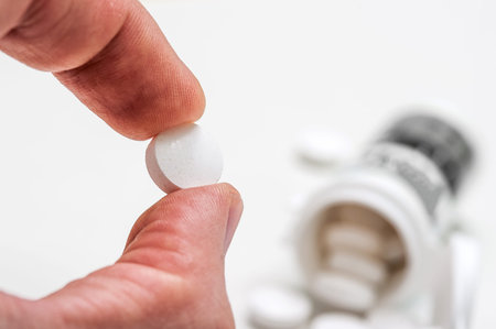 Fingers hold a medical pill from a package on a white background, pharmaceuticals, a Bank of pills...