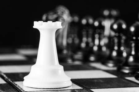 Chess pieces, a white rook on a chessboard, against a row of black pieces. The concept of career, competition, startup. High quality photoの写真素材