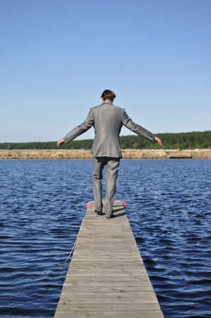 man in a gray suit walking on the pier, from the backの写真素材