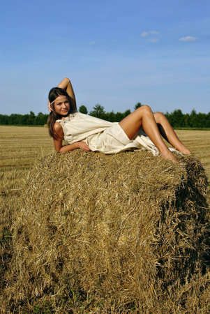 girl in a rural clothing lying on the haystack. space for textの写真素材