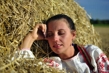 girl in traditional Russian costume resting on a haystackの写真素材