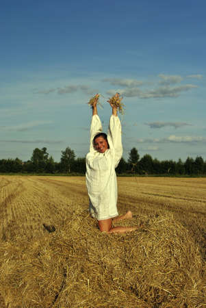 girl in traditional Russian costume sitting on a haystack, space for textの写真素材