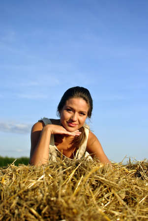 girl in traditional Russian costume resting on a haystack. space for textの写真素材