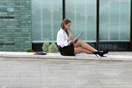Business woman sitting in a black skirt and sign the documentの写真素材