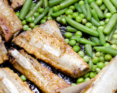 Pork ribs with peas and green beans prepared in a frying panの写真素材