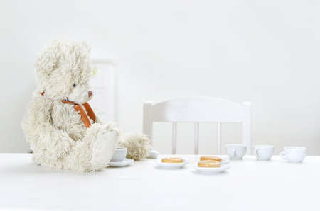Teddy bear drink tea with bagels at the table.の写真素材