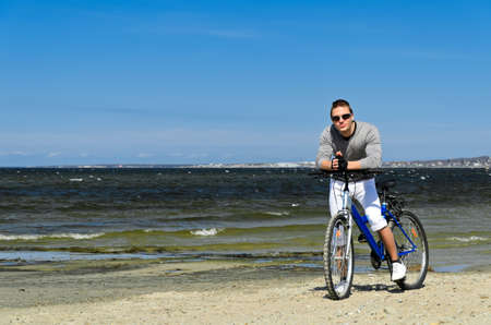 Portrait of handsome male with bicycle by the seaの写真素材