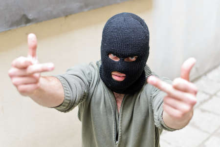Burglar wearing a mask shows fuck gesture.の写真素材