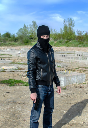 Thug in a mask with a gun in his hand