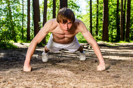 Attractive man doing a push up in forestの写真素材
