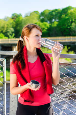 Attractive woman drinking water on the bridgeの写真素材