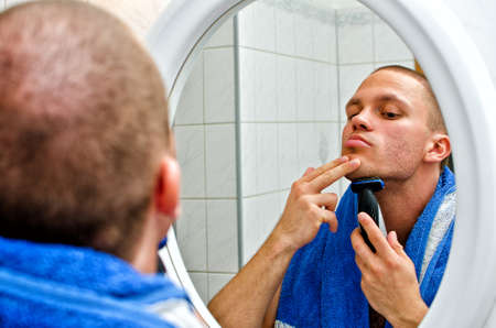 Male with towel shaving in bathroom in front of the mirror. の写真素材