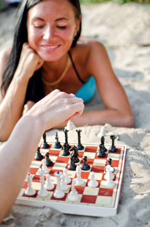 Portrait of pretty woman playing chess on the beachの写真素材