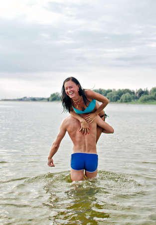 Man carrying woman on shoulder in the seaの写真素材