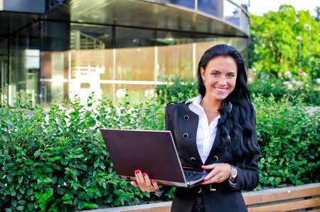 Businesswoman with notebook in city parkの写真素材