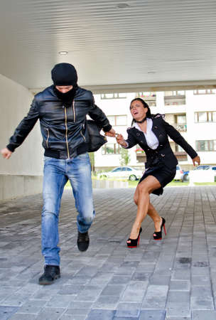 Bandit stealing businesswoman bag in the streetの写真素材