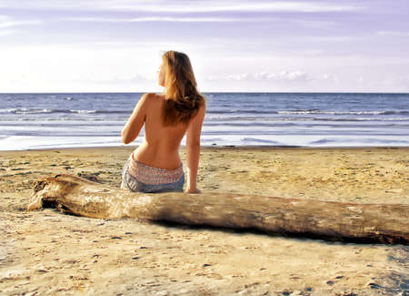 Back view of semi nude woman on the beachの写真素材