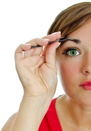 Young attractive woman plucking her eyebrows with tweezers  Isolated on whiteの写真素材