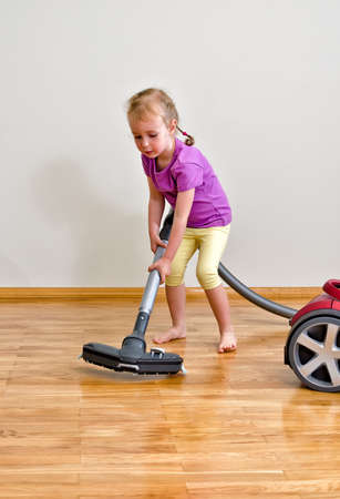 Cute little girl cleaning floor with vacuum cleanerの写真素材
