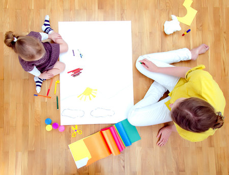 Young woman and little girl drawing together sitting on the floor  Top viewの写真素材