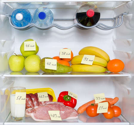 Open fridge full of fruits, vegetables and meat with marked caloriesの写真素材