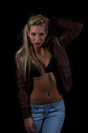 Sexy lady in bra and jeans posing over black backgroundの写真素材