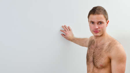 Portrait of handsome guy with bare torso against the wallの写真素材