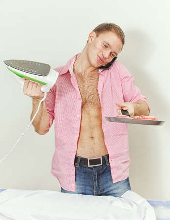 Young man with pan and iron speaking on the phoneの写真素材