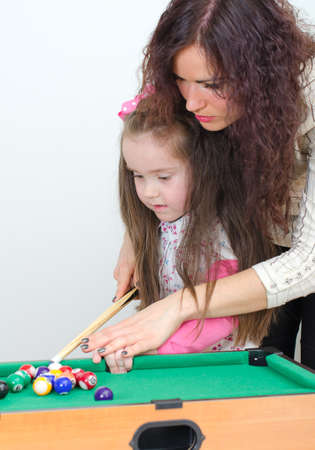 Mother teaching daughter play billiardの写真素材