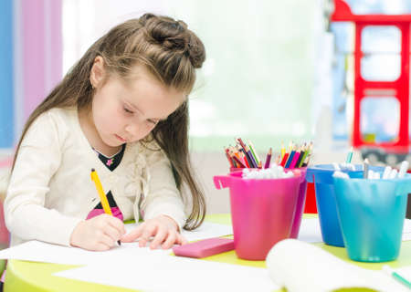 Little girl is drawing with pen in preschoolの写真素材